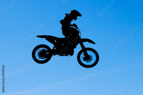 motocross rider making a high jump against a blue sky