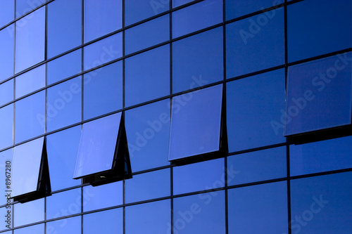 open windows on blue glass wall of a modern building photo