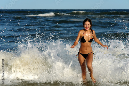 Beautiful young woman playing with waves on the ocean beach © sborisov