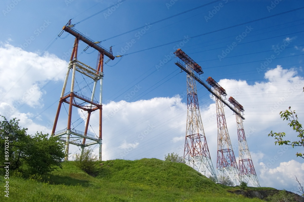 Electric main in the field against the cloudy sky