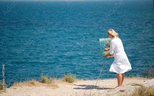 Woman painter during creation on sea side photo