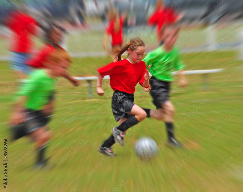 Young children running while playing soccer