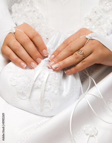 hands of a young bride with a small white bag