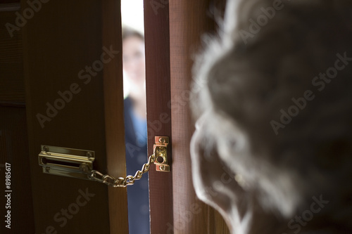 Obraz na płótnie Senior woman using a security chain on front door