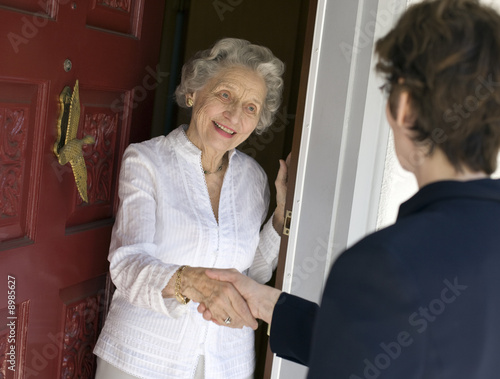 Smiling senior woman greeting visitor at the front door