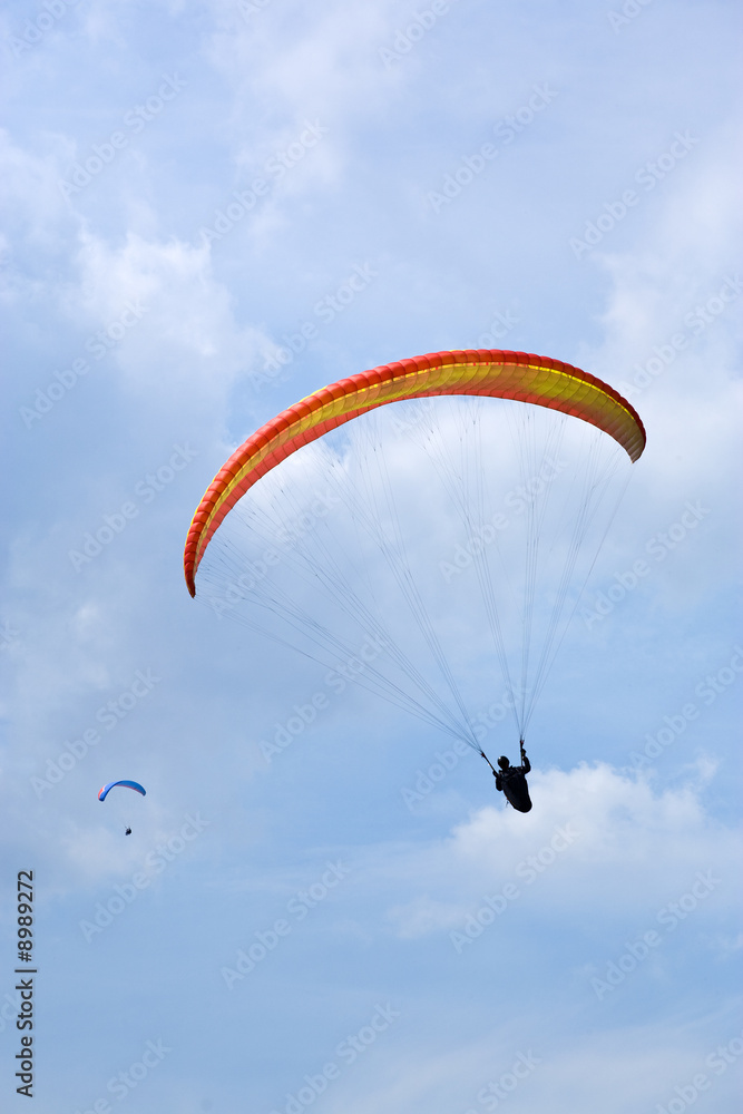 two paragliders silhouetted against summer sky two paragliders silhouetted against summer sky