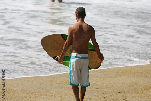 homme avec une planche de skimboard au bord de l'eau