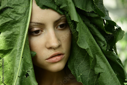 portrait of young beautiful girl with big leaves on head