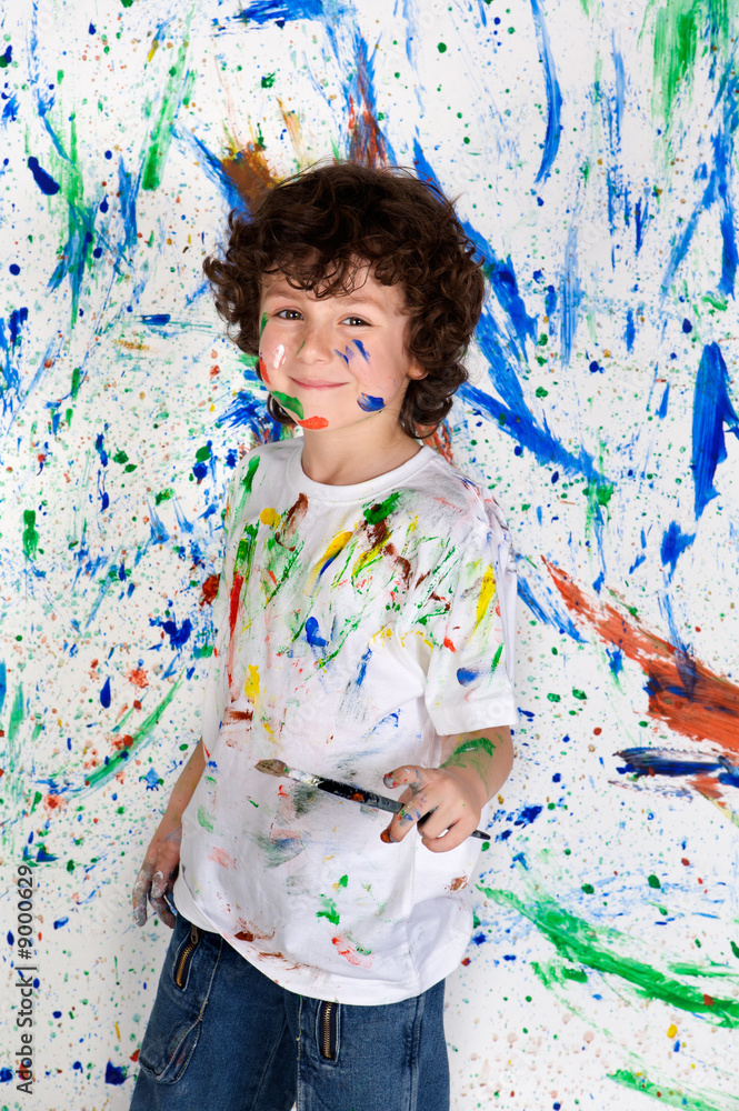 Handsome boy playing with painting with the background painted Handsome boy playing with painting with the background painted
