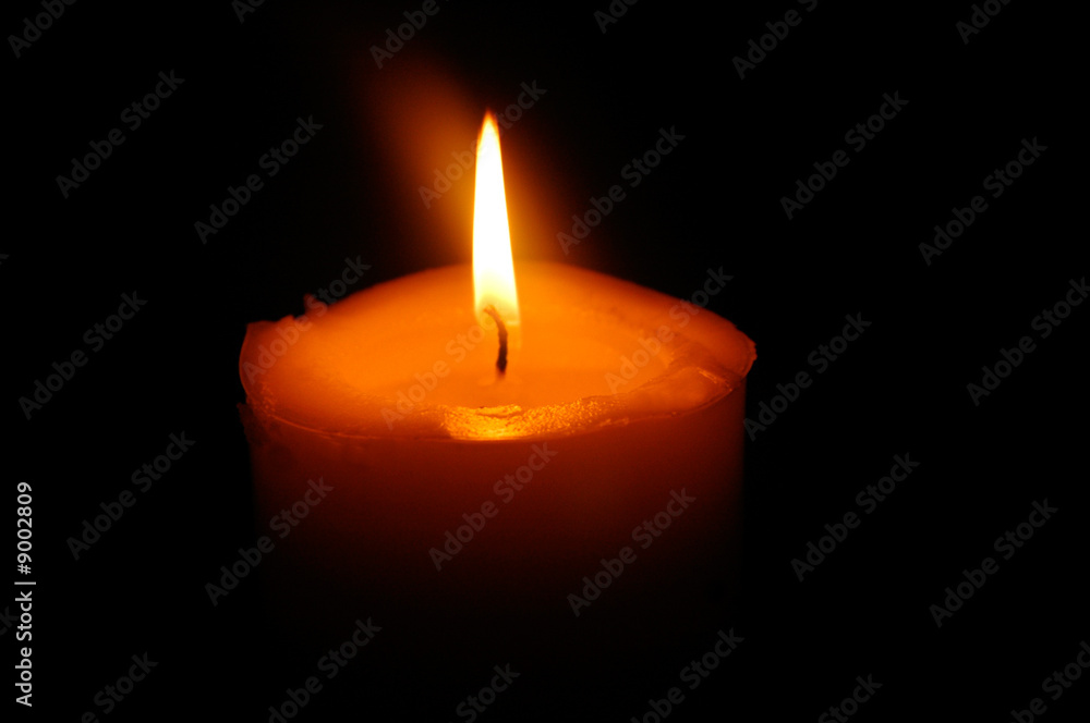 Solitary orange candle shining in the darkness. Solitary orange candle shining in the darkness.