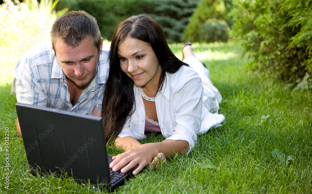 couple lying on grass with laptop couple lying on grass with laptop