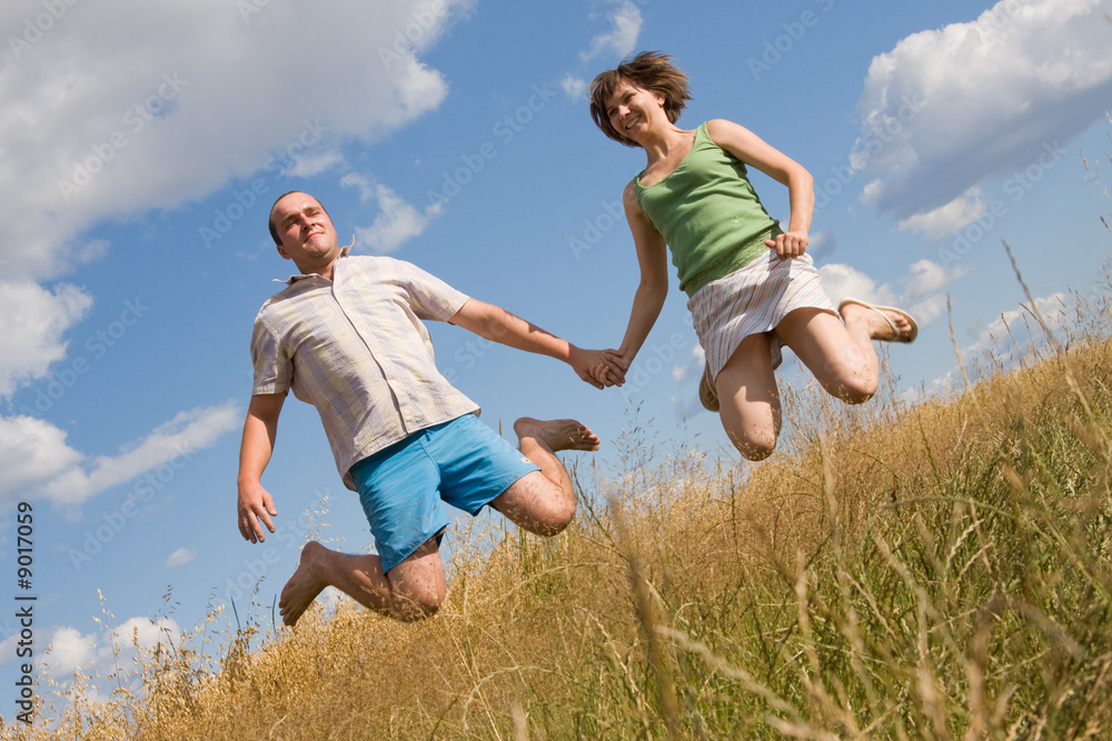 happy couple jumping together on a summer day happy couple jumping together on a summer day