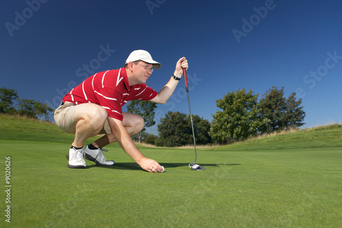 caucasian golfplayer concentrating before putting on golfcourt