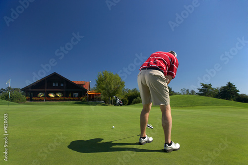 Foto caucasian golf player putting in front of clubhouse