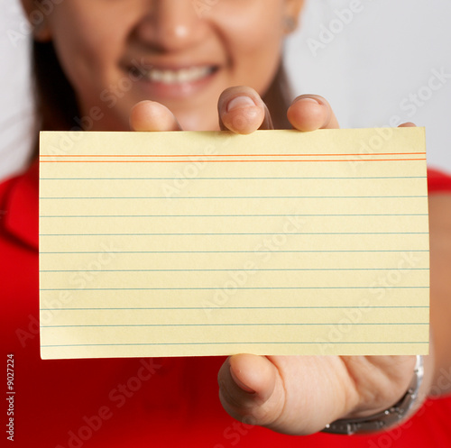 smiling woman holding a blank yellow notecard