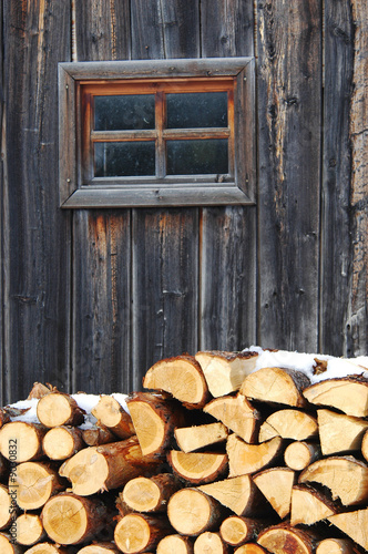 A pile of wood near wall in winter