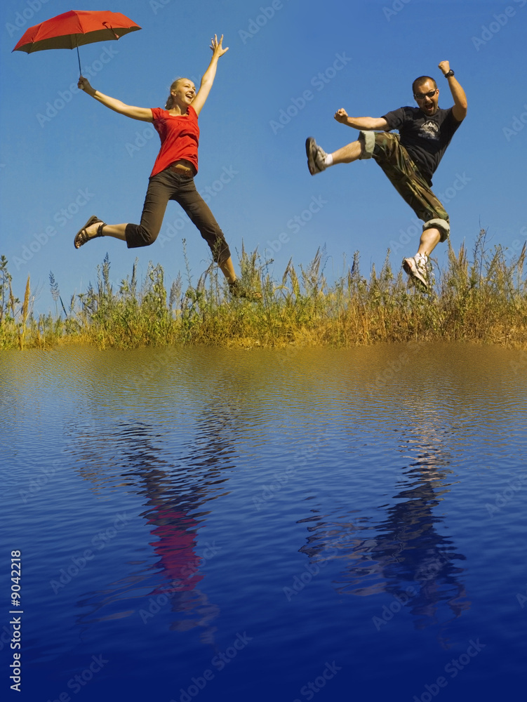 young people jumping on a meadow - water reflection