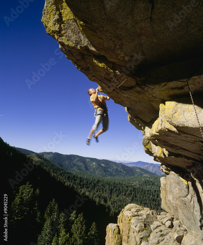 Rock climber dangling from a cliff.