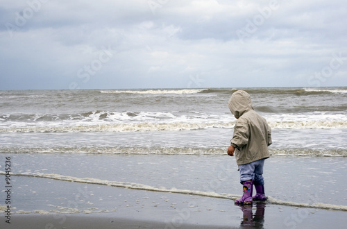 Petite fille marchant avec ses bottes dans la mer