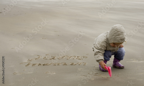Fille écrivant j'aime maman sur le sable