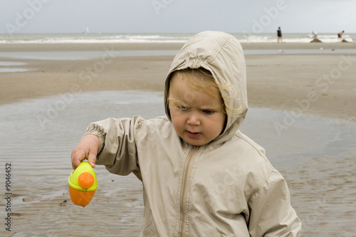 File qui renverse son arrosoir sur la plage