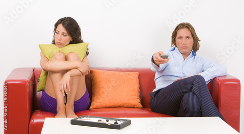 Young bored couple sitting on the sofa in their home