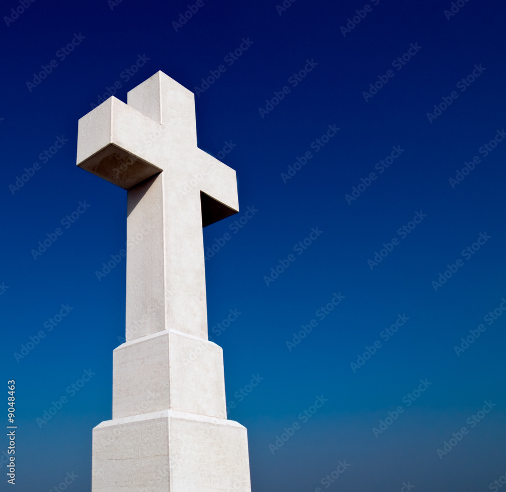 Big stone cross against a blue sky. Copy space on the right.