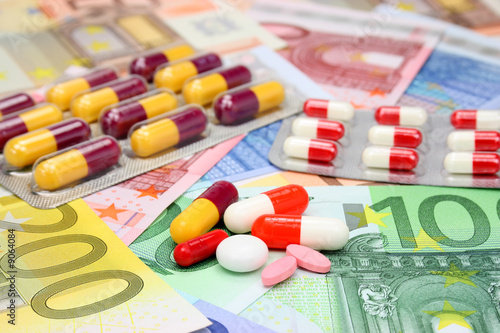 Assorted pills and capsules over euro money.