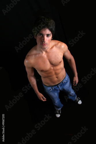 Handsome young man in dark from above wearing just jeans