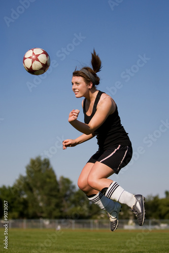 A female soccer player heading the ball
