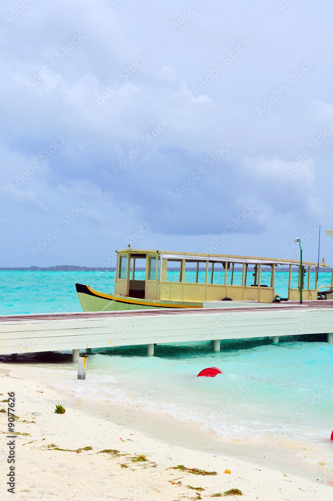 Old traditional boat anchored on a sandy beach in Maldives