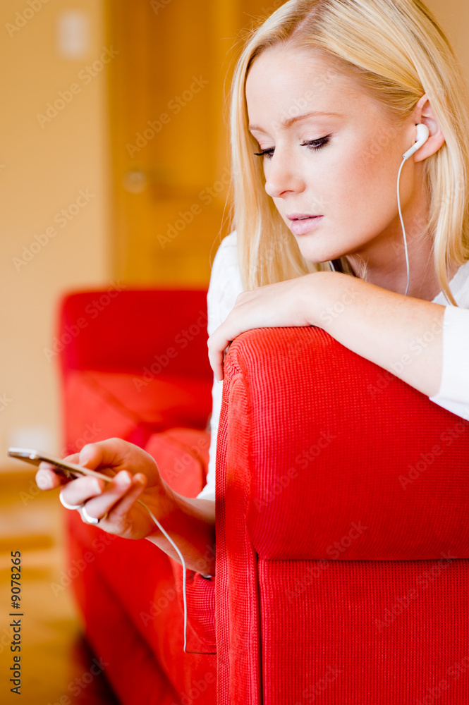 © EastWest Imaging - A young attractive woman lying on sofa listening to music