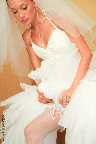 Portrait of elegant bride setting the garter straight