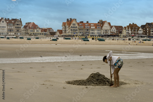 Enfant de dos faisant un château de sable photo