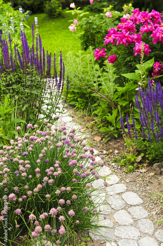 Lush blooming summer garden with paved path #9093459