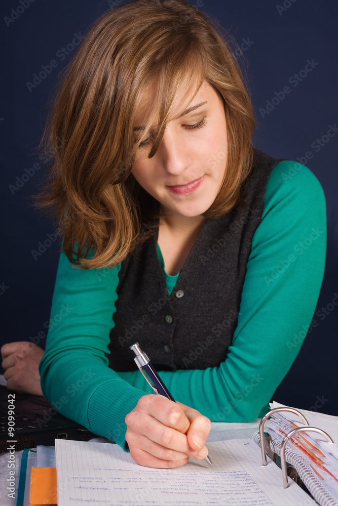 Teenager girl writing her homework in a notepad Teenager girl writing her homework in a notepad