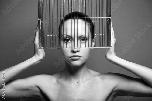 Surrealistic portrait of young woman with cage