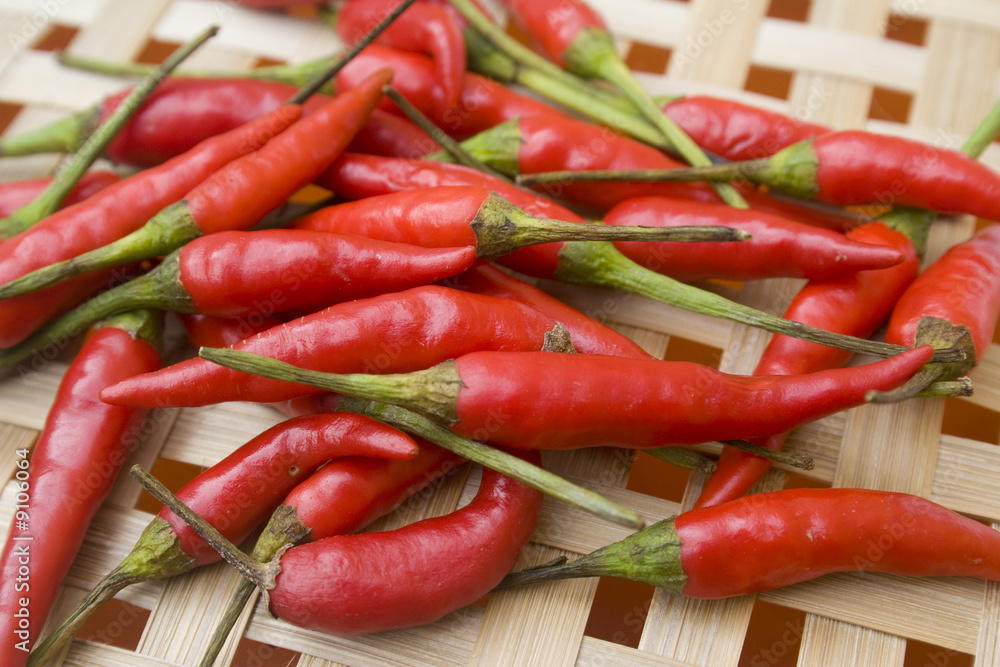 A pile of small red chili peppers on woven basket