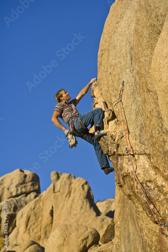 A rock climber clings to an overhanging rock face.