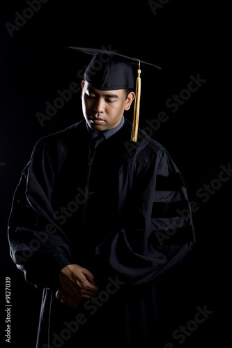 фотографія Low key image of a male model in graduation robes and regalia
