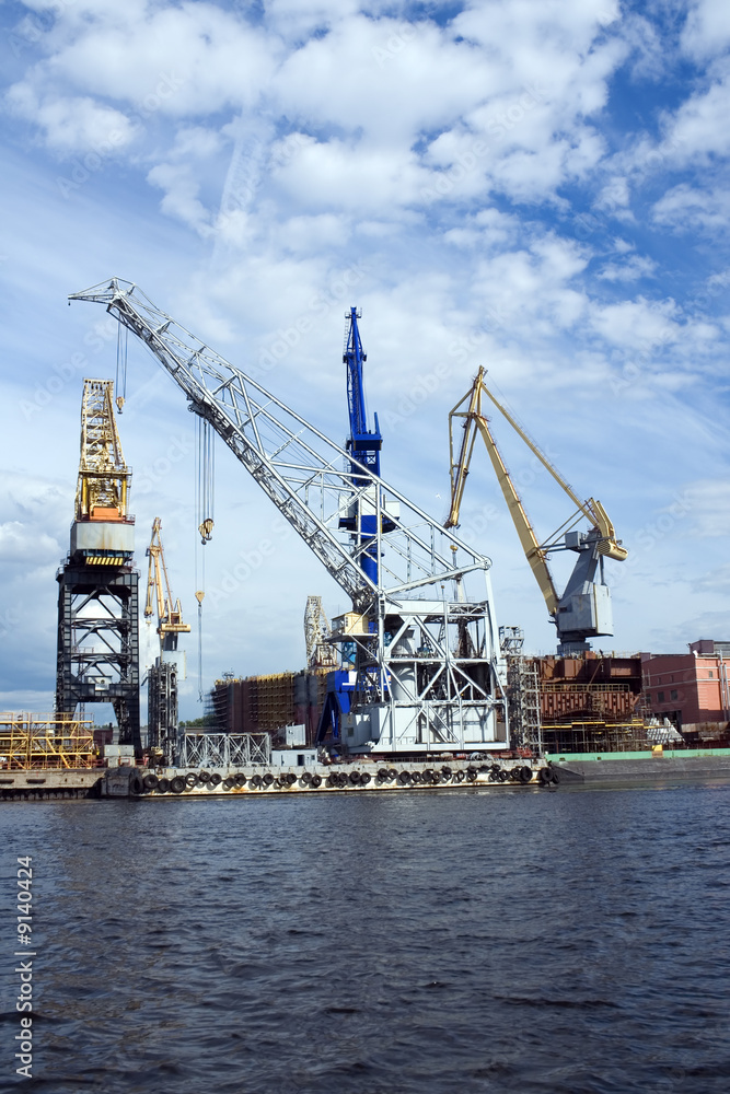 Large construction cranes in shipyard.