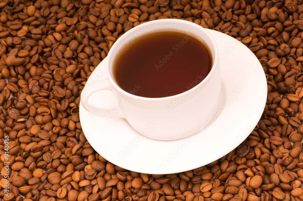 White cup on the background of coffee beans White cup on the background of coffee beans