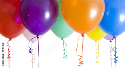 Close up of variety of balloons with ribbons brightly lit