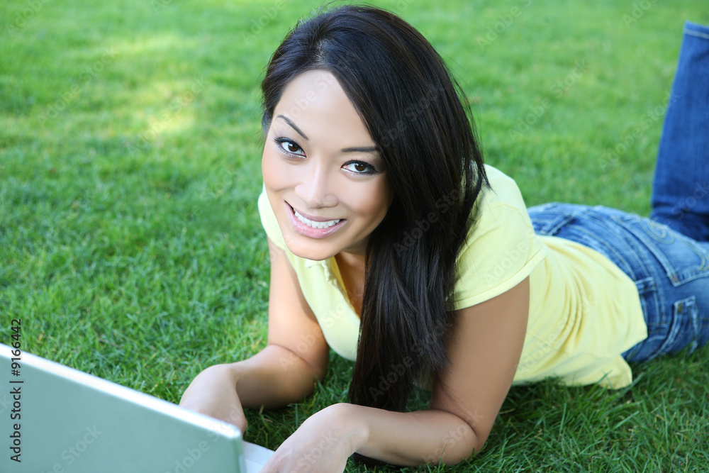 A pretty asian girl working on laptop computer on grass A pretty asian girl working on laptop computer on grass
