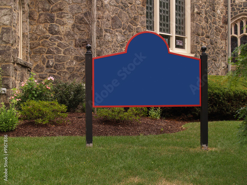blank sign by a stone church and grass lawn