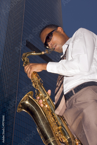 Urban saxophone player on skyscraper background photo