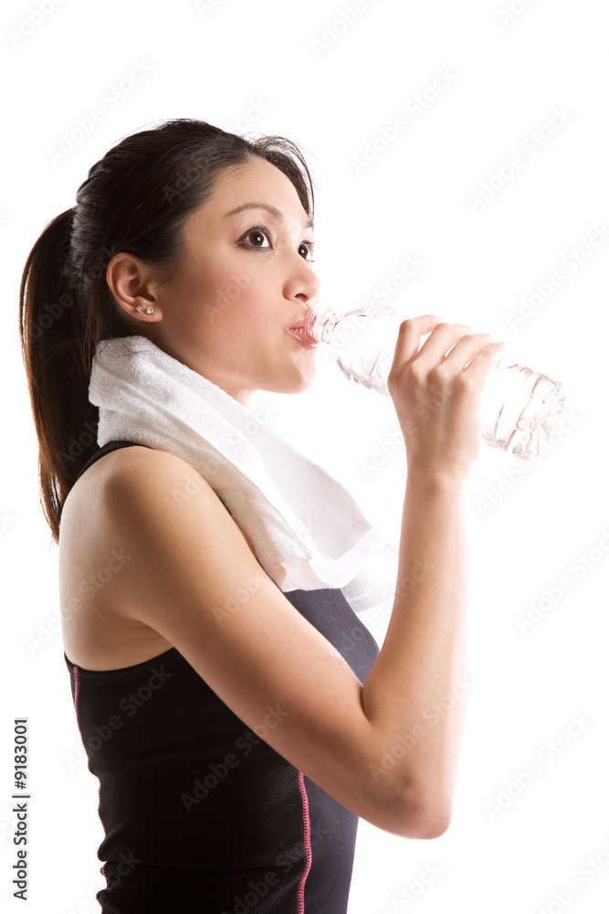 An isolated shot of an asian girl drinking water after exercise An isolated shot of an asian girl drinking water after exercise