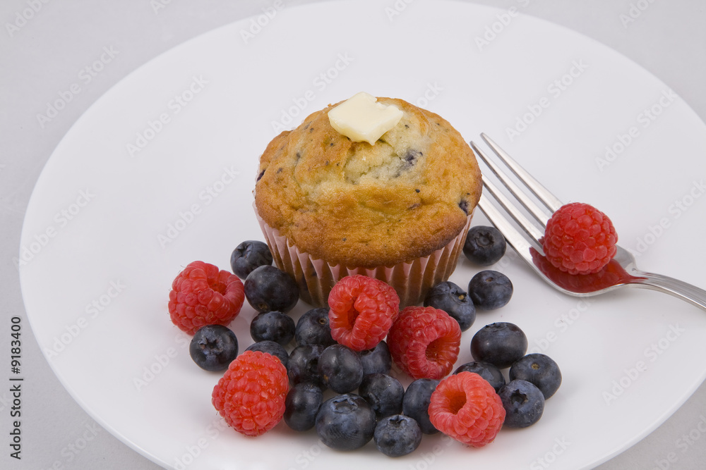 Hot muffins & fresh berries on white plate with fork.