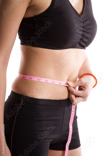 An slim and fit girl measuring her waist with a measuring tape