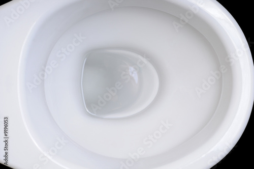 Detail of clean white toilet bowl on black background.